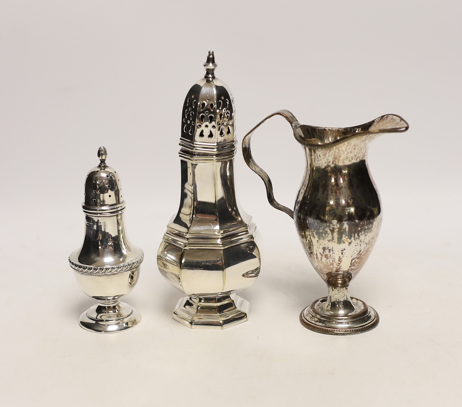 A George V silver pepperette, a silver plated sugar caster and a plated on copper cream jug.